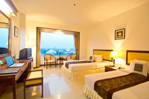 a hotel room with two beds and a desk at Champasak Grand Hotel in Pakse