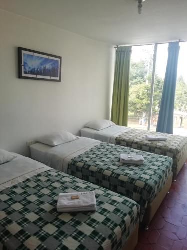 a hotel room with two beds and a window at Hotel Mónaco de Fusa in Fusagasuga