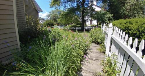 a garden next to a white fence with flowers at The Gables of Rhinebeck in Rhinebeck