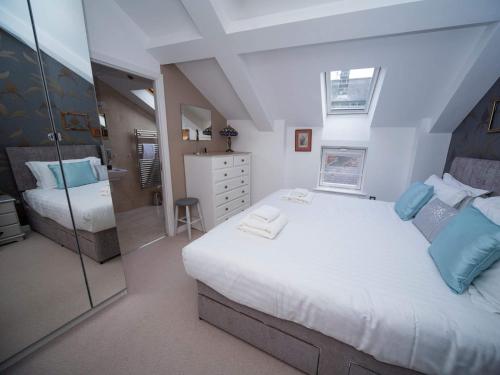 a bedroom with a large white bed with blue pillows at Regent Penthouse in Harrogate