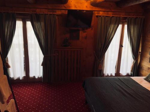 a bedroom with a bed with curtains and a television at Le Coin Savoyard in Combloux