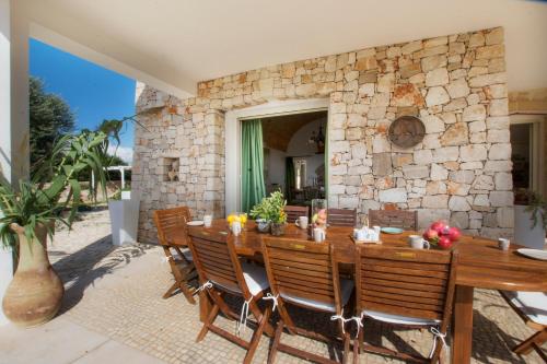 a stone walled patio with a wooden table and chairs at Le Gioie - Villa Macchia Mediterranea - Splendida villa vista mare immersa nel verde in Torre Pali 