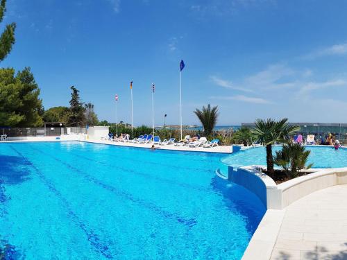 a large blue swimming pool with people sitting in chairs at Hotel Gabbiano Beach in Vieste