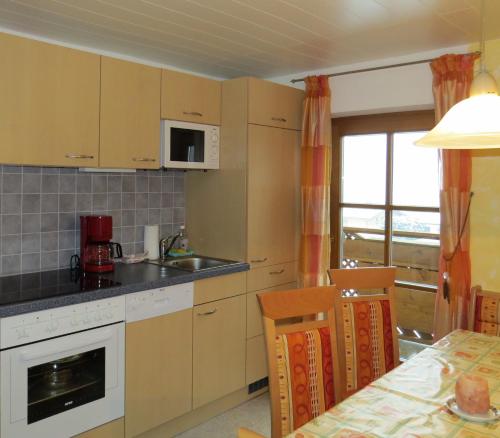 eine Küche mit einer Spüle, einer Mikrowelle und einem Tisch in der Unterkunft Biohof Haus Wieser in Abtenau