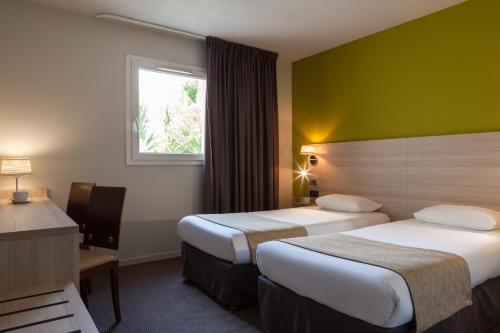 um quarto de hotel com duas camas e uma janela em The Originals City, Hôtel Les Bruyères, Dax Nord (Inter-Hotel) em Castets
