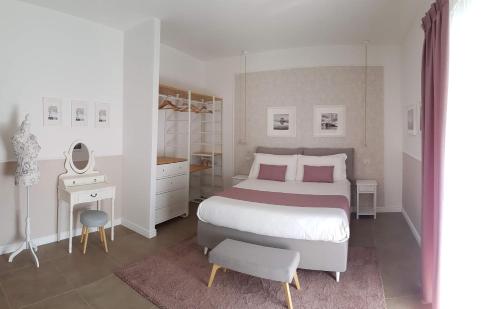 een witte slaapkamer met een groot bed en een spiegel bij a Casa di Ele in Napels
