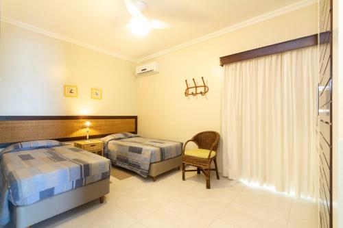a hotel room with two beds and a chair at Morada Baden Baden in Bombinhas