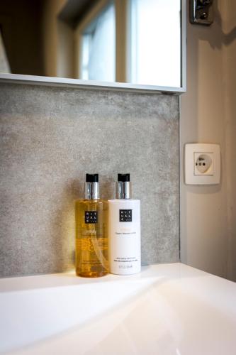 two bottles ofodorizers sitting on a counter under a mirror at The Piano Guesthouse - Kwaadham52 in Ghent