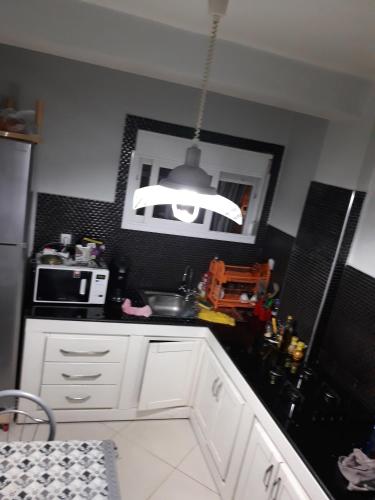 a kitchen with white cabinets and a pendant light at Appartement Akid Lotfi Oran in Oran