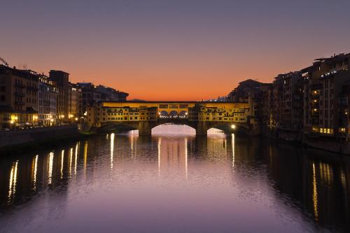 a bridge over a river in a city at night at Appartamento Signoria in Florence