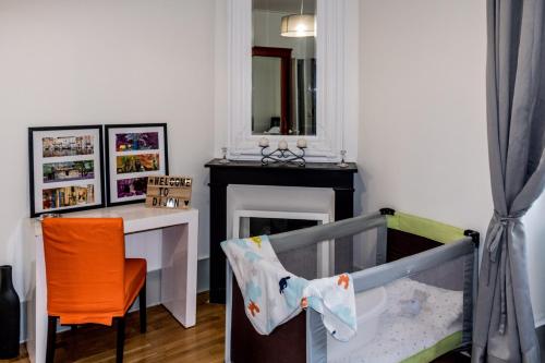 - une chambre avec un lit bébé, une table et une chaise dans l'établissement La ptite chouette, à Dijon