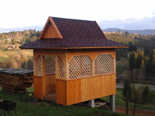 a gazebo with a roof on top of a field at Romashka Guest House in Yablunytsya