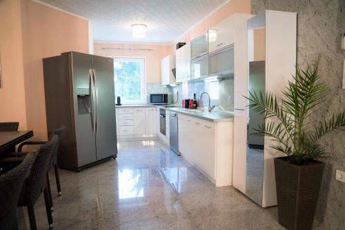 a kitchen with a stainless steel refrigerator and white cabinets at BRILLWELLNESS in Zalakaros