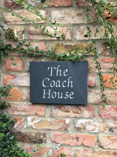 a sign that says the coach house on a brick wall at The coach house in Grimston