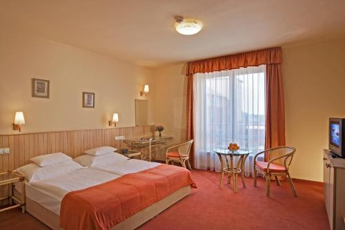 a hotel room with a bed and a table at Termálhotel Martfű in Martfů