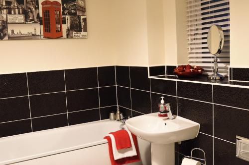 a bathroom with a white sink and a bath tub at StayNEC Coach House Birmingham - For Company, Contractor & Leisure Stays - NEC, HS2, JLR, Airport in Birmingham