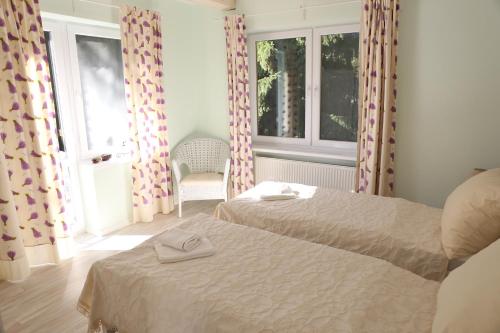 a bedroom with two beds and a chair and windows at Apartmánový dom Harmónia in Modra