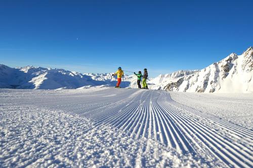 three people are skiing down a snow covered mountain at Catrina Hotel in Disentis