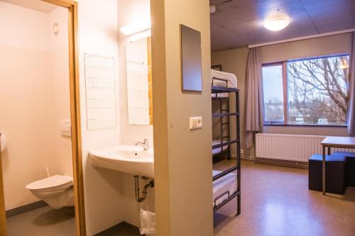 a bathroom with a sink and a toilet and a bunk bed at Dalur - HI Eco Hostel in Reykjavík