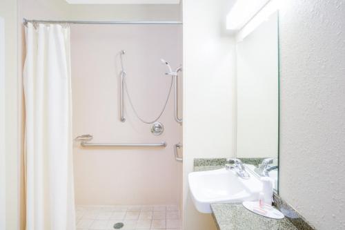 a bathroom with a shower, sink, and mirror at Microtel Inn & Suites by Wyndham Saraland in Saraland