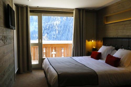 クールシュヴェルにあるホテル エデルヴェスのベッドと大きな窓が備わるホテルルームです。
