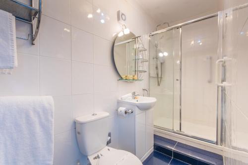 a bathroom with a toilet and a sink and a shower at Grovefield Manor in Poole