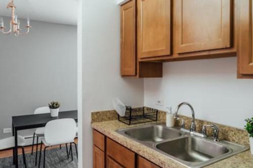 a kitchen with a sink and a table with a chair at 1BR Stylish Apartment, Perfect for Getaway - Oakdale 201 in Chicago