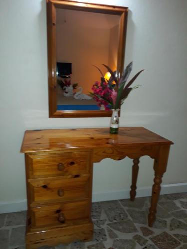 a wooden table with a mirror and a vase of flowers on it at Paradise Inn in Port Antonio