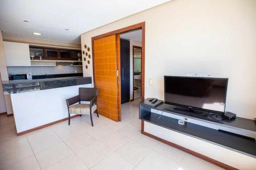 sala de estar con TV de pantalla plana y cocina en Kariri Apartaments Sunset Beach, en Cumbuco