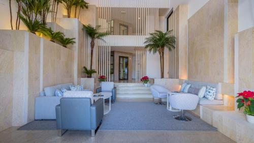 a lobby with blue chairs and tables and palm trees at Quinta do Lago Country Club in Quinta do Lago