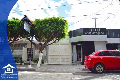 a red car parked in front of a hotel law center at Hotel y Apartments Los Cisneros in Managua
