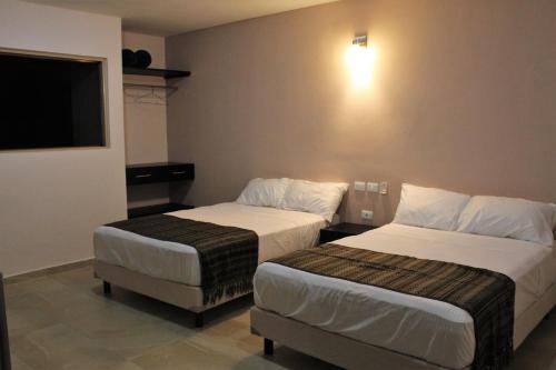 a hotel room with two beds and a flat screen tv at Hotel Virreyes in Mérida