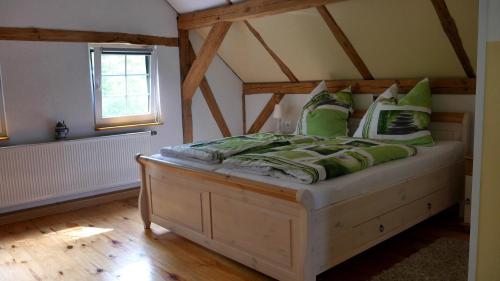 ein Schlafzimmer mit einem Bett mit grünen Kissen in der Unterkunft Wjažka in Guhrow