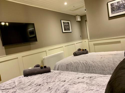 a bedroom with two beds and a flat screen tv at The Tower Arms Hotel in Iver