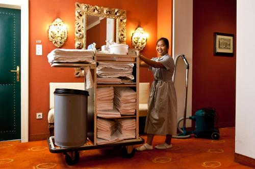 a woman standing next to a towel cart with towels at Hotel Regina in Vienna