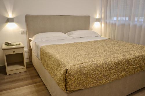 a bedroom with a large bed and a side table at Hotel Tiffany in Marina di Massa