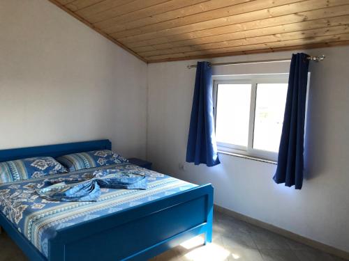 a bedroom with a blue bed and a window at Doci Seven Hotel in Velipojë
