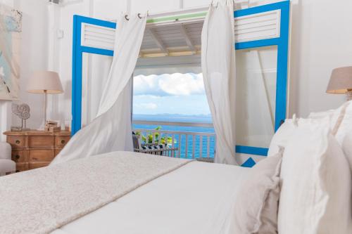 a bedroom with a bed and a view of the ocean at Casa la Colline in Vieux-Fort