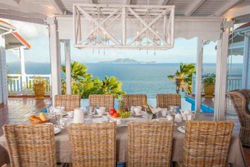 a dining room with a table with a view of the ocean at Casa la Colline in Vieux-Fort