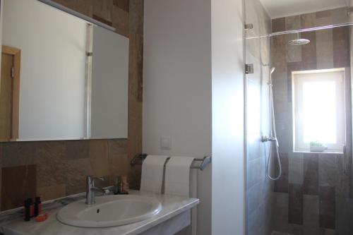 a bathroom with a sink and a shower with a mirror at Monte das Perdizes in Olhão