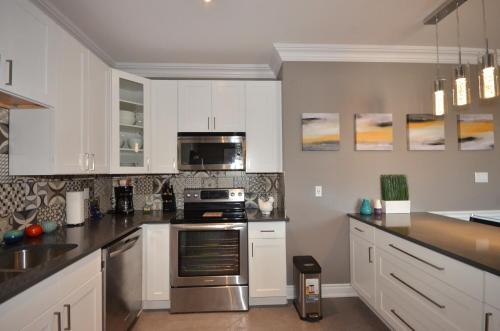 a kitchen with white cabinets and stainless steel appliances at The SoMa Furnished Residences in Hamilton