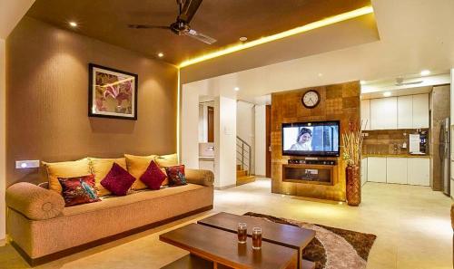 a living room with a couch and a tv at Mrudgandh Pool Villa Girivan Near Pune Mumbai in Mulshi