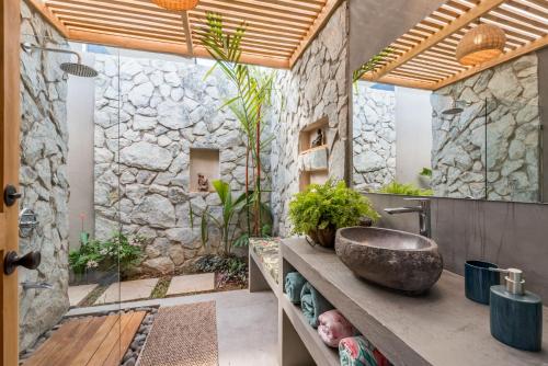 a bathroom with a sink and a stone wall at Zen Garden Tamarindo - Adults Only in Tamarindo