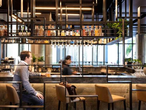 a man sitting at a bar in a restaurant at Novotel Brisbane South Bank in Brisbane