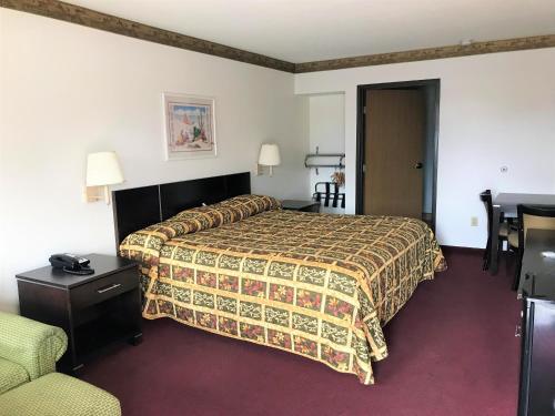 Habitación de hotel con cama y silla en American Inn & Suites en Albuquerque
