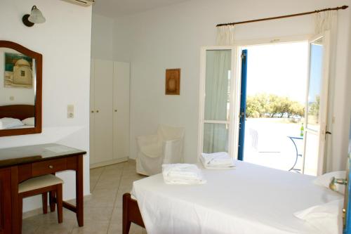 1 dormitorio con cama, escritorio y espejo en Blue Bay Villas en Kamari