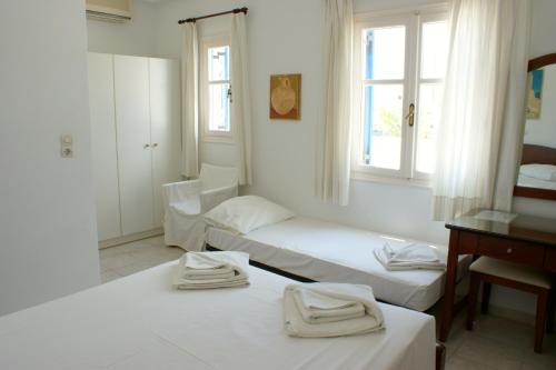 a room with two beds and a desk and window at Blue Bay Villas in Kamari