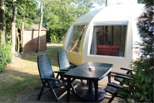 a picnic table and chairs in front of a trailer at Iglo Bungalow 93 in Chaam