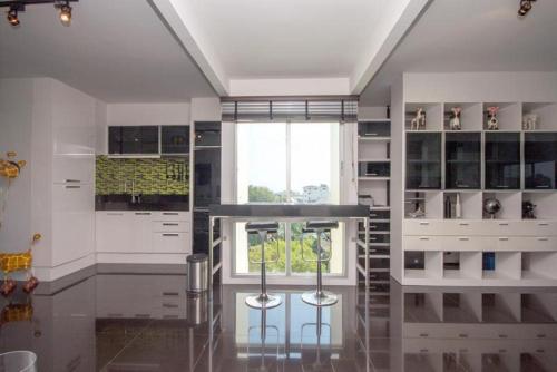 a kitchen with two bar stools and a window at Flame Tree Suite 110 sqm 2-Bedroom Apartment in Hua Hin