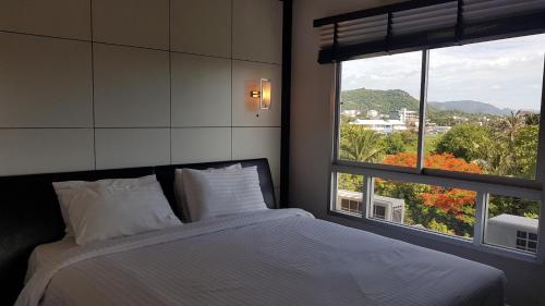 1 dormitorio con cama y ventana grande en Flame Tree Residence 2-Bedroom Apartment, en Hua Hin